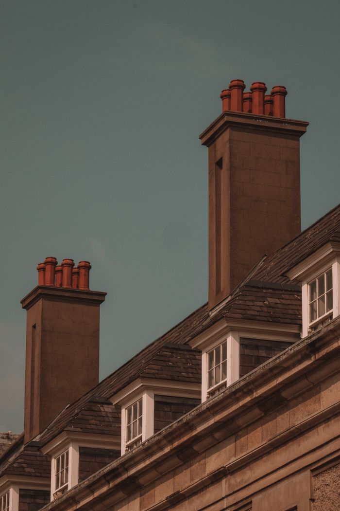 A view of classic urban rooftops showcasing prominent red brick chimneys under a clear sky.
