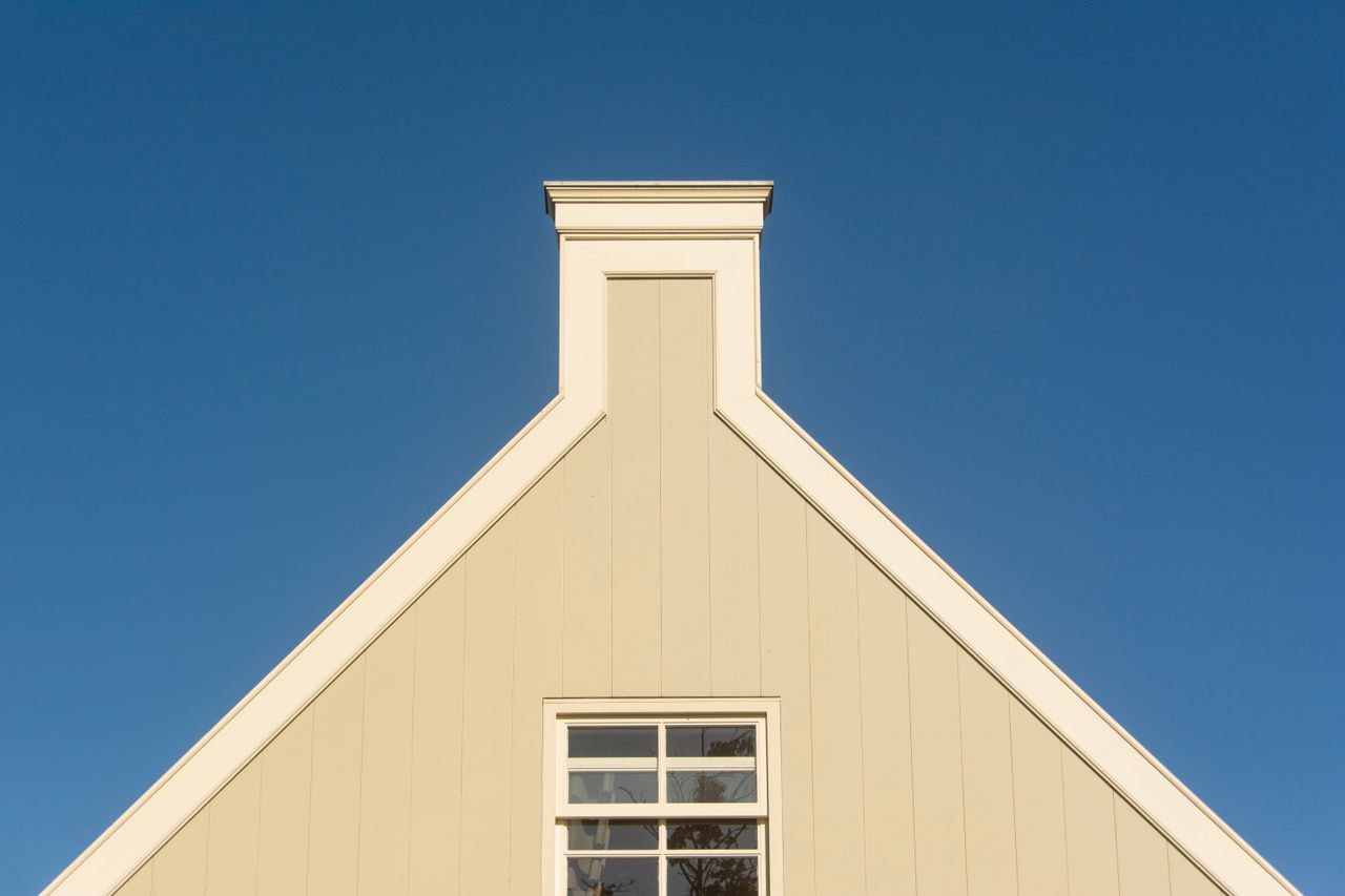 Triangular house facade against a clear blue sky, showcasing minimalist architecture.