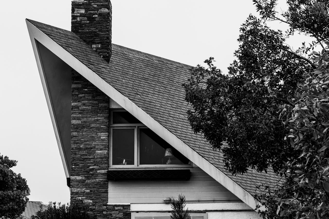 Black and white photo of an A-frame house with a distinctive steep roof and large window.